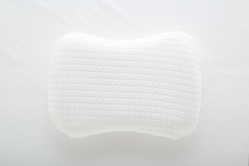 New soft memory foam pillow with white cover on mattress background. Closeup. Top down view.