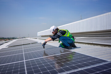 Blue collar worker is inspecting solar panel at rooftop of factory.