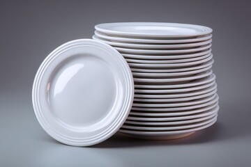 Stacked white plates with one plate leaning against the pile against a neutral background in an indoor setting