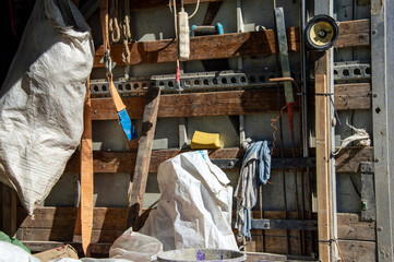 Various tools and materials are organized on a wooden wall in a workshop, with a white bag and...