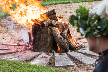 Close-up of a campfire, large burning logs and red flames on a summer solstice evening in a rural setting.