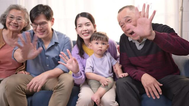 Happy multi-generational Asian family enjoying quality time together at home, cheering and smiling with a toddler
