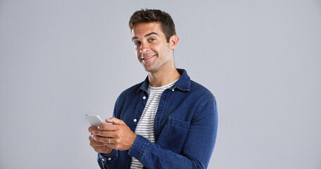 Portrait, happy man and typing with mobile in studio for social media or text on white background. Phone, smile and person with message on app for download, network and blog post with mockup space