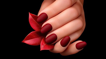 Hand holding red leaves with matching maroon colored nails