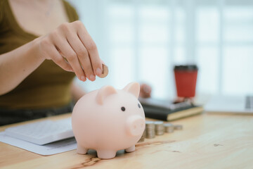 Woman putting money in piggy bank, money saving concept
