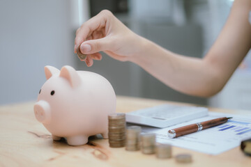 Woman putting money in piggy bank, money saving concept

