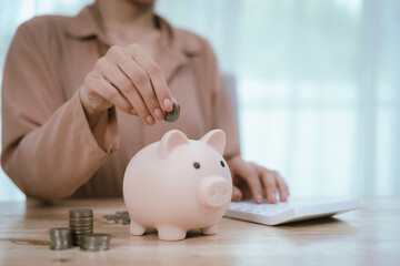 Money saving ideas: woman puts money in a piggy bank, analyzes expenses