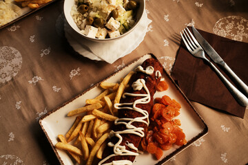 Close-up of crispy meat roll served with golden fries and stewed carrots, traditional Serbian dish...
