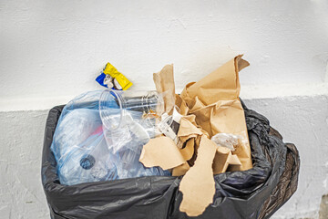 full trash can in a public place with eco bags