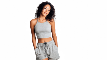 Young, fit woman with curly hair showcasing a grey sports outfit, her hands casually in her pockets, against a transparent background, ideal for fitness, fashion, or lifestyle promotions