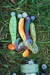 Silicone wobblers on the grass near the spinning rod. Fishing tackle. Set of colorful silicone lures. Close-up