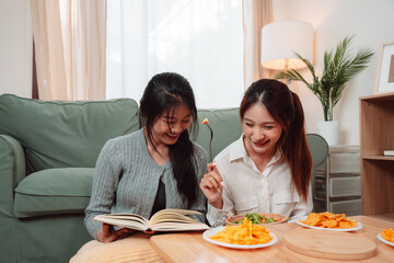 Asian Women Snack Food Eating Lifestyle Indoor Living Room Enjoyment Movie, Two Young Adults Sharing Laughter and Snacks While Watching TV, Embracing Friendship and Relaxation at Home Together
