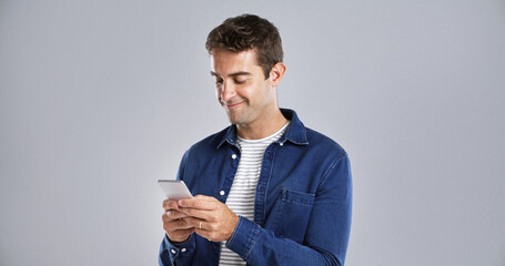 Smile, phone and man in studio for typing, text or reading message on white background space. Mobile, happy person or check email online on app for notification, play game or social media on internet