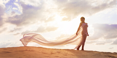 Graceful Mature Woman in Flowing Fabric at Sunset Beach