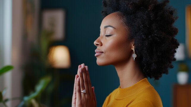 A moment of peaceful meditation or prayer, featuring an individual with their eyes closed and hands together, likely in a room with calming elements.