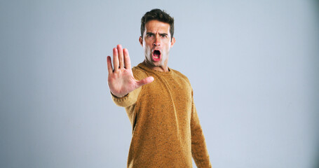 Naklejka premium Warning, stop and portrait of man in studio for rejection, deny or no hand gesture for protest. Shout, serious and male person with palm for caution, safety or self defense by gray background.