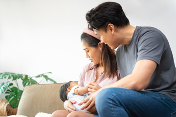 Loving New Parents Gazing at Their Newborn Baby, Young Asian Couple Adoring Their Infant Child at Home, First Time Parents Cherishing Moments with Their Baby