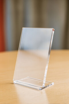 Clear acrylic sign holder stand displaying blank card on neutral background