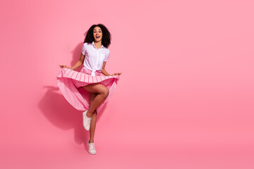Cheerful young woman wearing a stylish pink skirt and white shirt posing against a pink background...