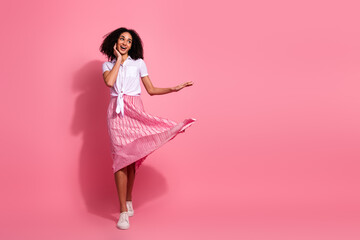 Cheerful young woman modeling a casual chic outfit on a pink background, embracing vibrant fashion...