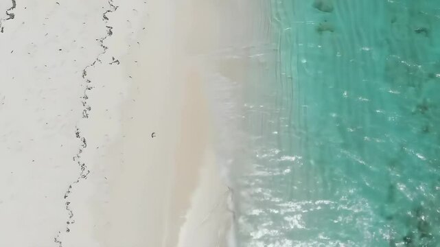 Top Down Aerial View of White Sand Beach and Turquoise Ocean Waves Gently Crashing