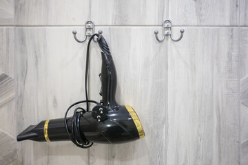 Wall-mounted hair dryer hanging in a modern bathroom with tasteful decor and contemporary design...