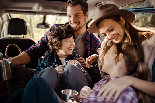 Happy family sitting in car taking pictures during road trip