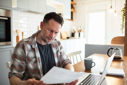Man looking stressed while reviewing bills at home office