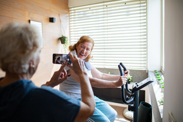 Senior lesbian couple exercising together at home and cheering each other on