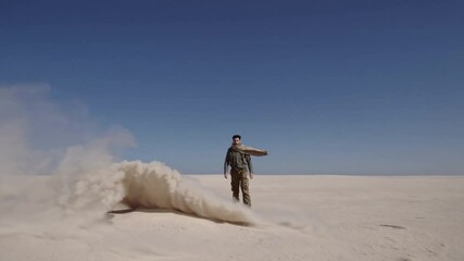Sand swirling intensely as lone traveler navigating harsh desert landscape with determined stride under expansive blue sky - Powered by Adobe