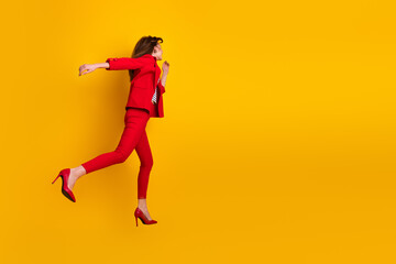 Fototapeta na wymiar Confident young woman in a red suit gracefully posing against a vibrant yellow background, expressing elegance and fashion.