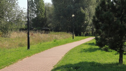 Sentiero al parco comunale fatto di betonelle autobloccanti. La stradina in mezzo agli alberi. 