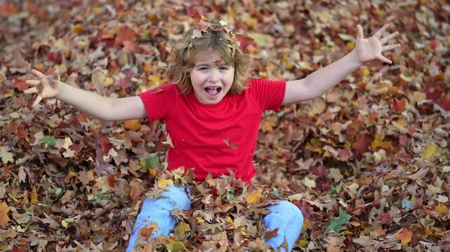 Autumn child throws leaves. Child throwing up leaf. Kid plays with leaves. Joyful autumn leaf toss. Child throws leaves up. Autumn child tossing leaf. Kid throwing leaves with joy. Autumn fall.