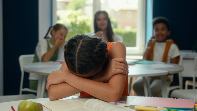 Caucasian kid child daughter pupil schoolgirl studying in classroom primary education lesson classmates cruel children bully student mock throw crumpled paper problem suffer abuse sad little girl cry