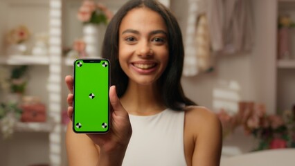 Latina American ethnic woman holding green screen mobile phone in bathroom smartphone chroma key copy space display holding smiling happy girl buying cosmetics online shopping purchasing beauty app