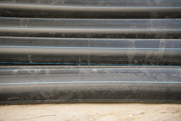 Black pipes stacked in a construction site showing motion blur from nearby activity and rushing work