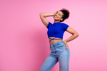 Lovely young woman in vibrant outfit posing confidently against a pink background radiating joy and...