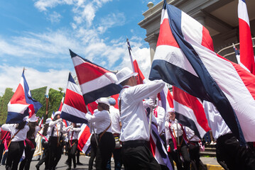 Students wave Costa Rican flags in a coordinated movement during a vibrant Independence Day...