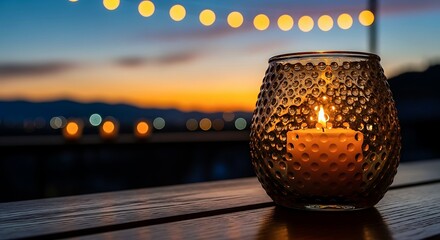 Warm candlelight in textured amber glass lantern on wooden outdoor table at sunset, with glowing string lights and bokeh background for romantic, cozy evening, celebration or relaxation mood