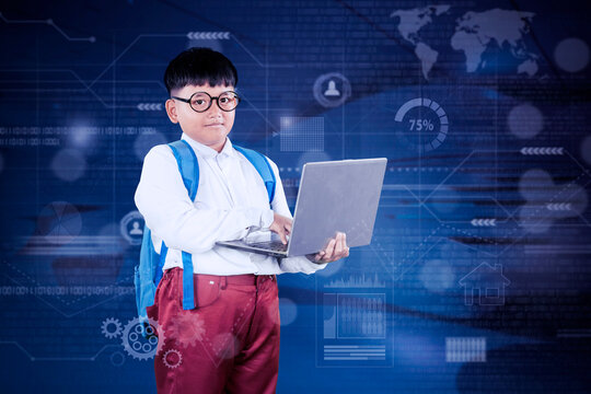 Smart Asian Schoolboy Using Laptop with Futuristic Digital Interface Background
