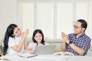 Happy Asian Parents Applauding Daughter's Online Learning Success at Home