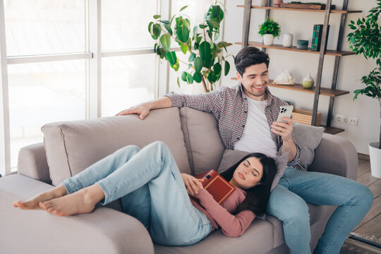 Young couple relaxing together on a cozy sofa at home, engaged in leisure activities and enjoying each other's company - Powered by Adobe