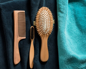 A wooden comb and brush set on a flatlay of teal and black towels