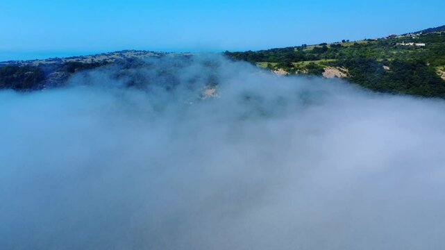 Aerial panoramic view of Cape Emine on the Bulgarian Black Sea coast. Dramatic cliffs, a historic lighthouse, and turquoise waters shrouded in mysterious sea mist, captured by drone.