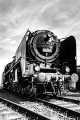 Steam locomotive of the legendary class 01 on a sunny day. Lovingly restored historic engine from a frog's-eye view. German railroad technology. Black and white vintage technology.