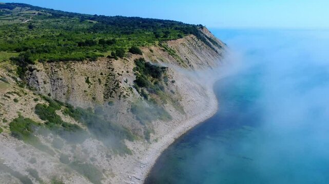 Aerial panoramic view of Cape Emine on the Bulgarian Black Sea coast. Dramatic cliffs, a historic lighthouse, and turquoise waters shrouded in mysterious sea mist, captured by drone.