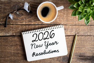 New year resolutions 2026 on desk. 2026 goals list with notebook, coffee cup, plant on wooden table. Resolutions, plan, goals, action, checklist, idea concept. New Year 2026 resolutions. Copy space