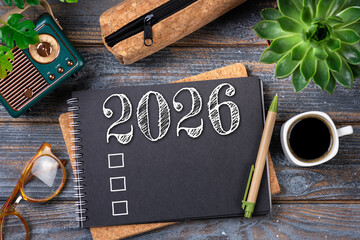 New year resolutions 2026 on desk. 2026 goals list with notebook, coffee cup, plant on wooden table. Resolutions, plan, goals, action, checklist, idea concept. New Year 2026 resolutions, copy space