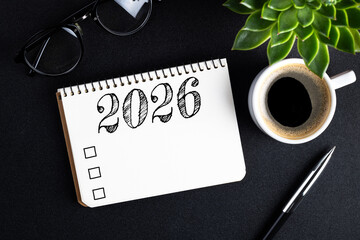 2026 New year resolutions on desk. 2026 goals list with notebook, coffee cup, plant on black table. Resolutions, plan, goals, action, checklist, idea concept. New Year 2026 resolutions. Copy space