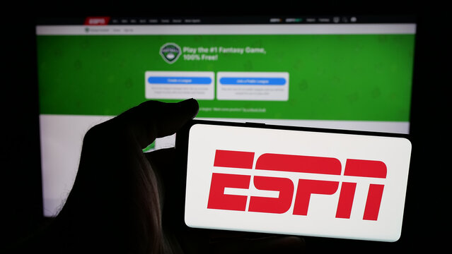 Stuttgart, Germany - 05-27-2025: Person holding mobile phone with logo of US cable sports television channel ESPN on screen in front of web page. Focus on phone display.